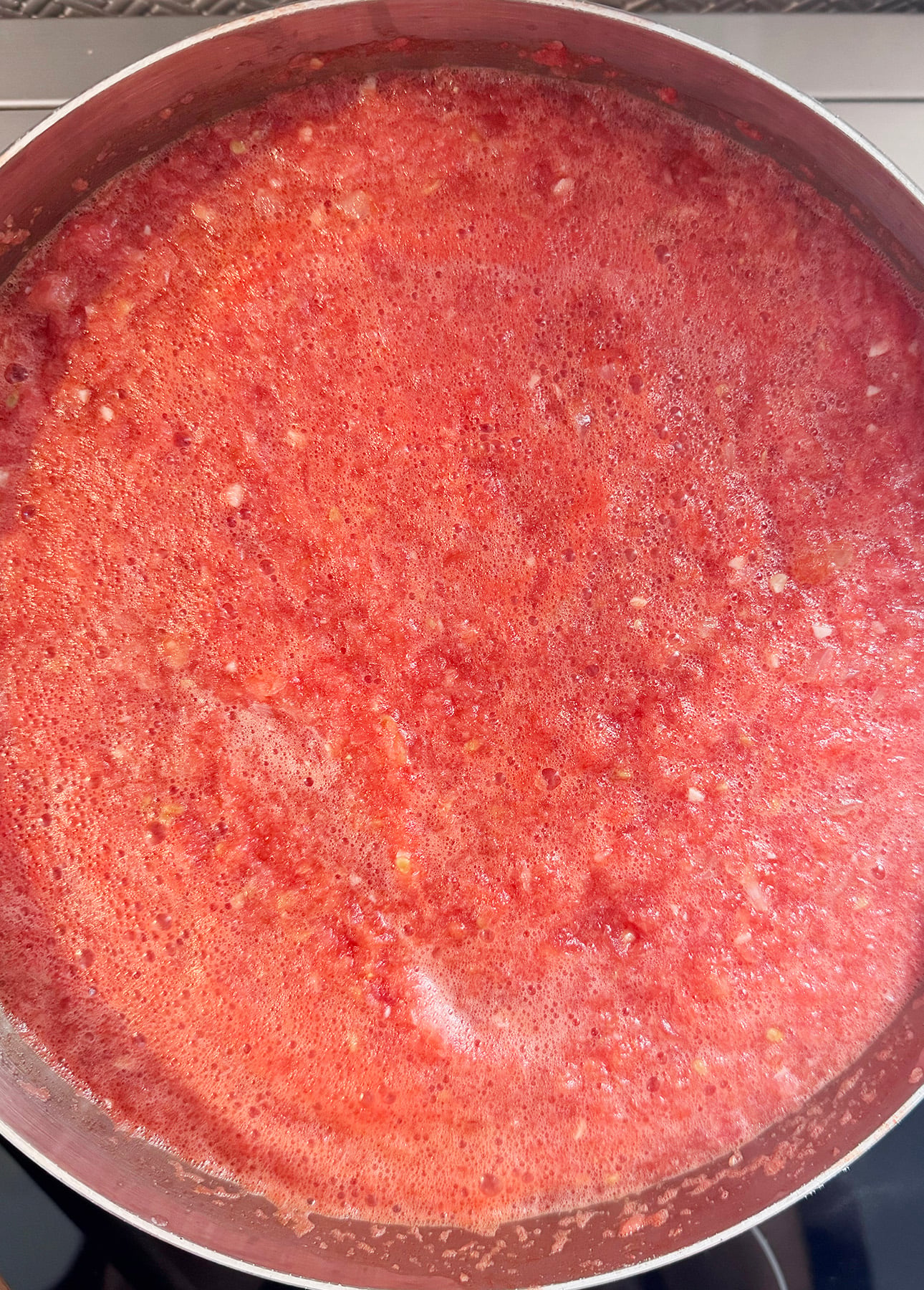 A close-up view of a pot filled with blended, frothy red tomato mixture, likely being prepared for a Fresh Tomato Sauce or soup. // FoodNouveau.com