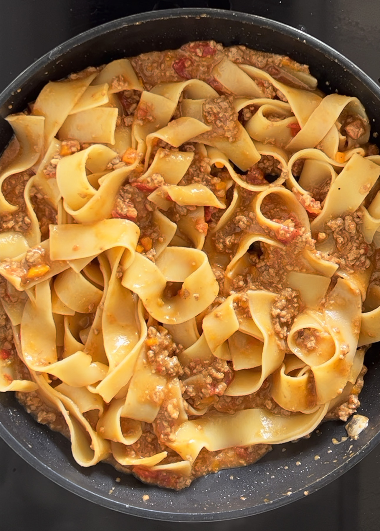 A skillet of pappardelle pasta with rich Bolognese sauce // FoodNouveau.com