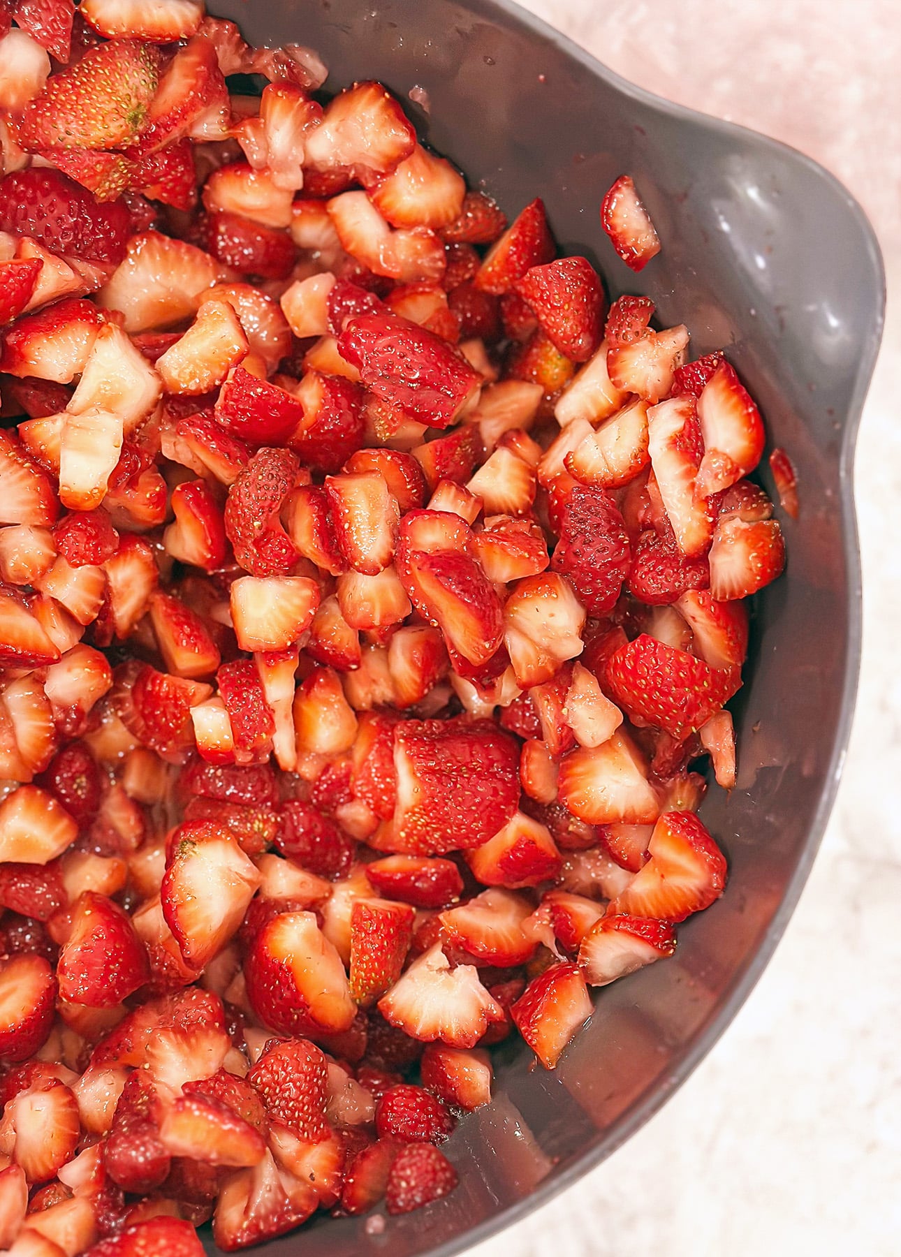 A close-up of a gray bowl filled with freshly diced strawberries on a light-colored surface, perfect for topping a citrus mousse. // FoodNouveau.com