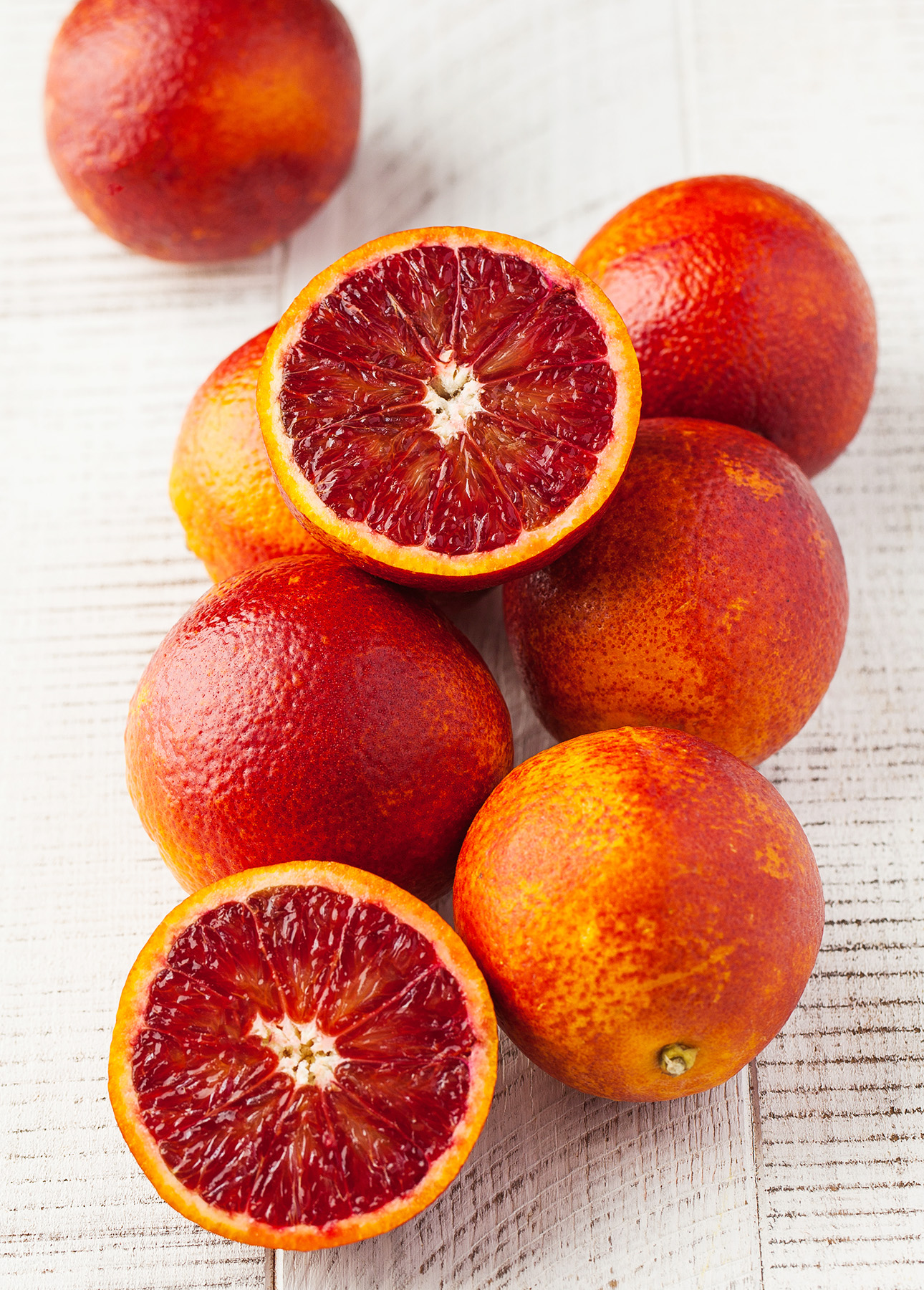 A group of juicy ripe red oranges on a white wooden background // FoodNouveau.com
